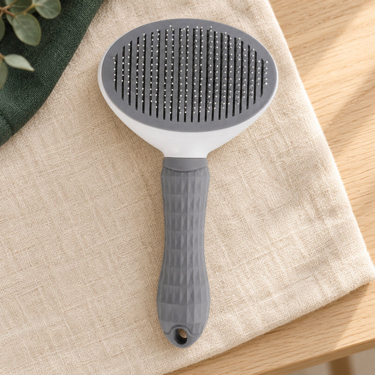 Brosse autonettoyante grise et blanche, picots fins et manche à facettes